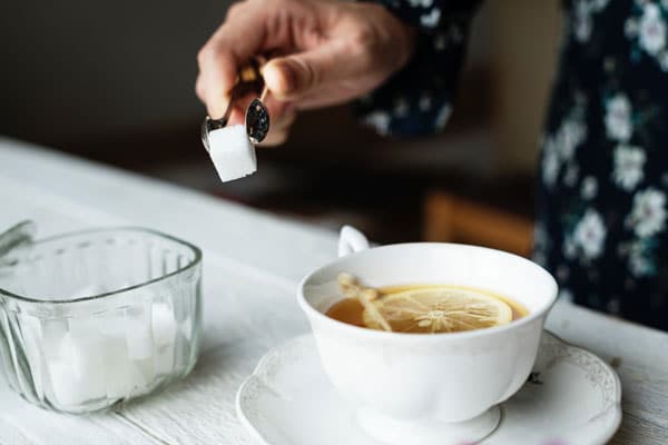 A sugar cube being dropped into a tea cup