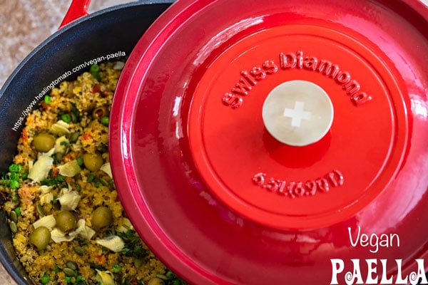 Overhead view of the dutch oven partially covering the vegan paella