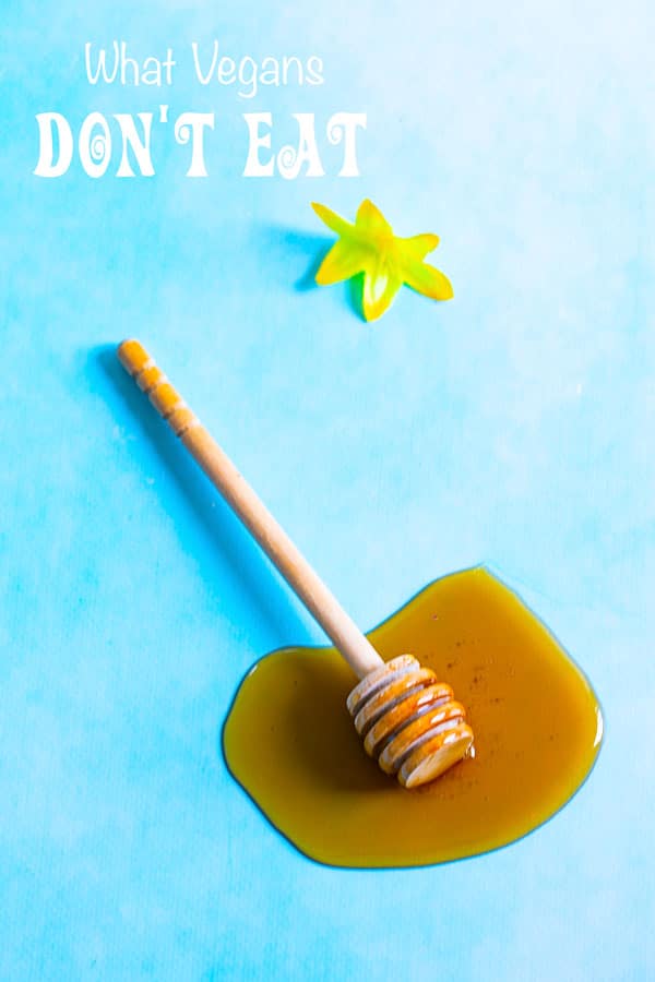 A honey dipper flat on a table with honey around it - What Vegans Don't Eat