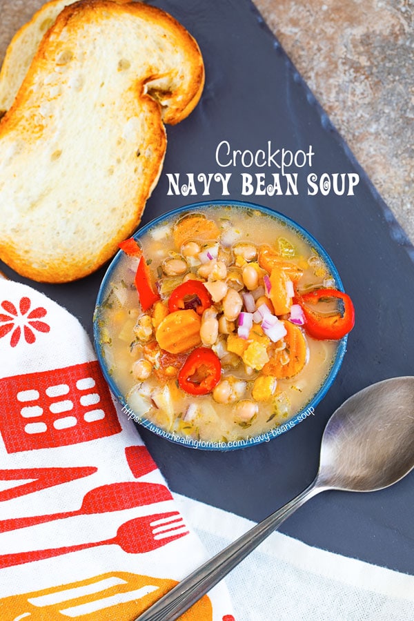 Top view of a blue bowl filled with navy bean soup with a spoon on the side