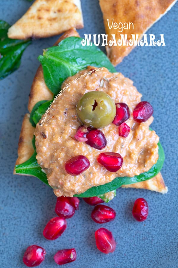Overhead view of pita chip loaded with muhammara and pomegranate