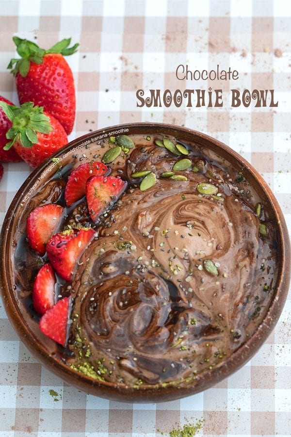 Top view of a brown bowl with chocolate banana smoothie. Garnish with strawberry and seeds
