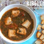 Overhead closeup of ribollita soup in a bowl and small bread cubes on the side