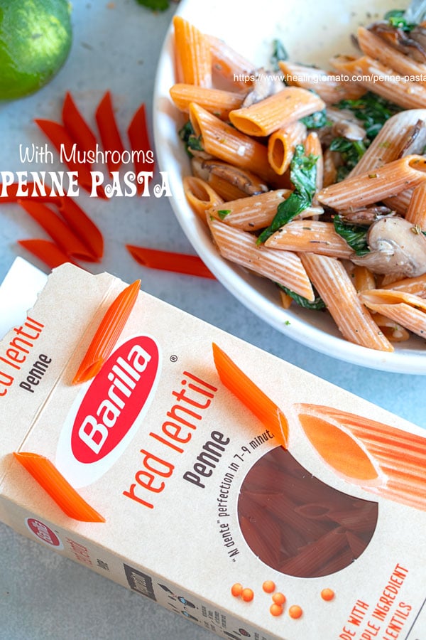 OVerhead view of a box of barilla red lentil pasta sitting next to a bowl of cooked penne pasta