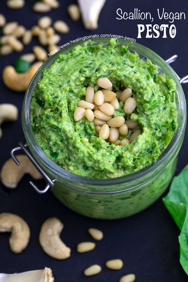 Closeup view of vegan pesto with scallions, cashews, basil and pine nuts strewn about