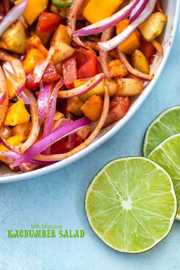 Closeup view of a light gray bowl with Kachumber salad in it and lime slices on the bottom right corner