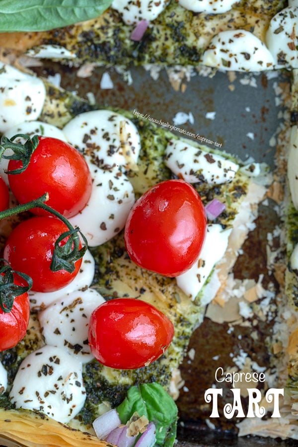 top view of cherry tomatoes on the vine on a phyllo dough tart with melted mozzarella balls