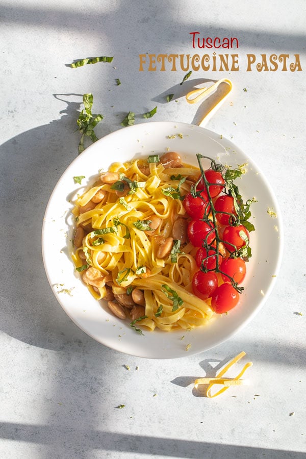 top view of tuscan fettuccine pasta with cherry tomatoes and basil for garnish