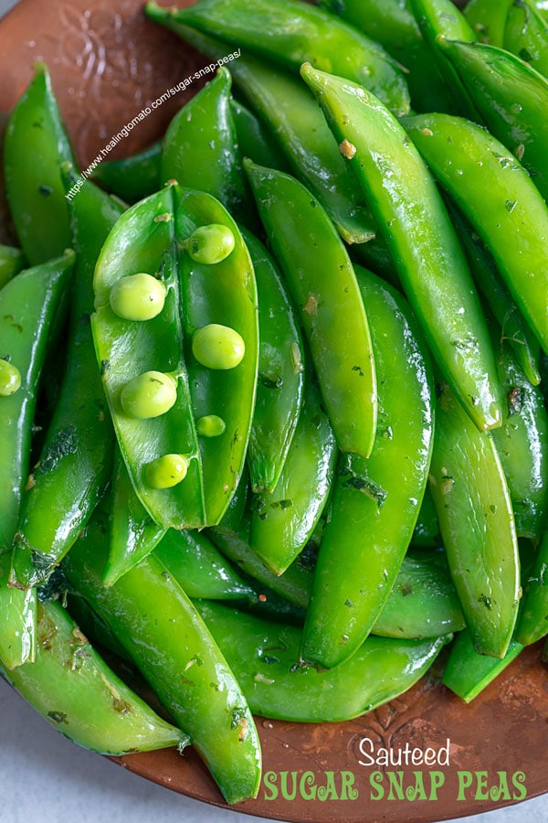 Top view of an open sugar snap pea pod with peas showing