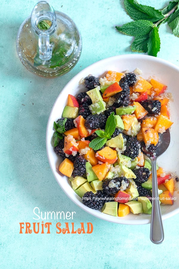 Top view of a white bowl with blackberries, peaches, avodado and quino