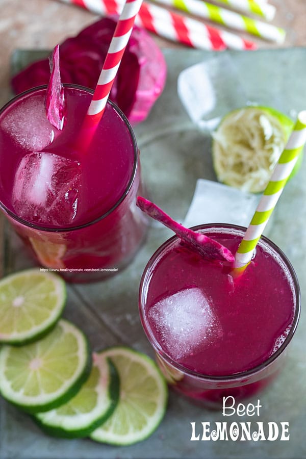 Top view of 2 small glasses filled with beet lemonade. Ice cubes inside, a red and green paper straw to the side and a slice of beet lemonade for garnish