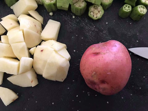 a baby potato next to cubed baby potatoes on a chopping board