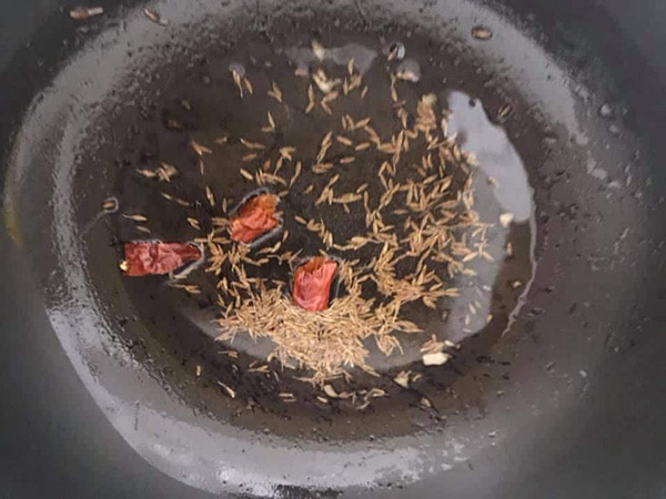 top view of cumin, dry whole chili in oil in a frying pan