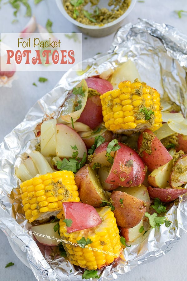 Top view of potatoes and mini corn on the cob inside an aluminium wrap