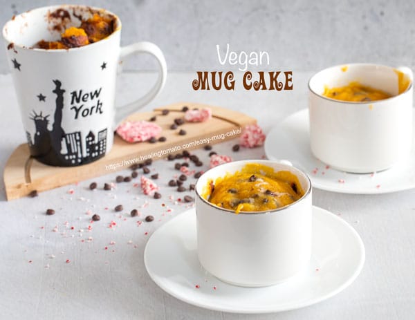 front view of 3 a mug filled with an easy mug cake. Two more mugs in the background and chocolate chips strewn around the mugs