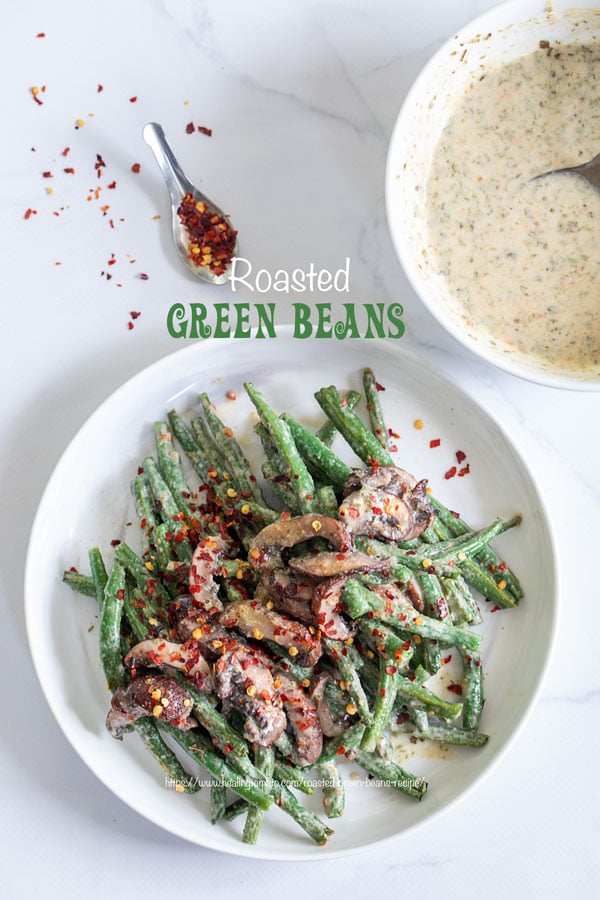 Top view of green beans and mushrooms in a white plate with red pepper flakes for garnish