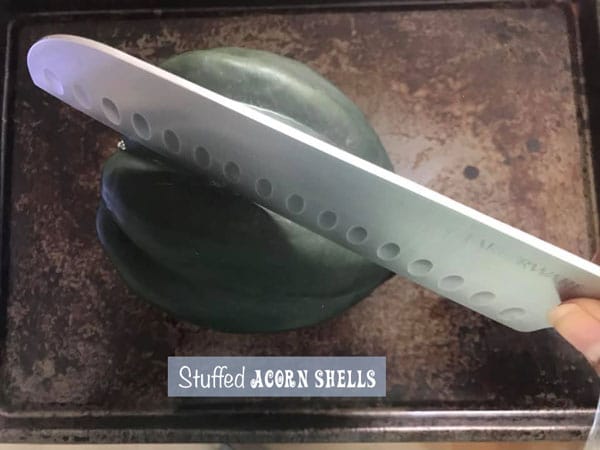 A large knife placed over a groove of an acorn squash