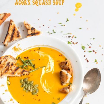 Top view of a white plate filled with acorn squash soup with garnish and grilled croutons