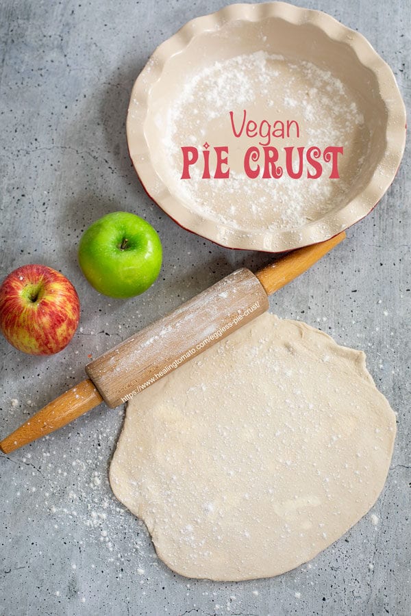Top view of a rolled pie crust with a rolling pin, apples, and pie pan on the side