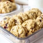 front view of a dozen oatmeal cranberry cookies lined up in a square glass containter.