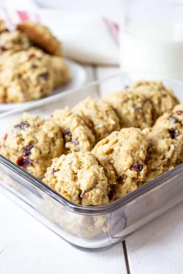 front view of a dozen oatmeal cranberry cookies lined up in a square glass containter. 
