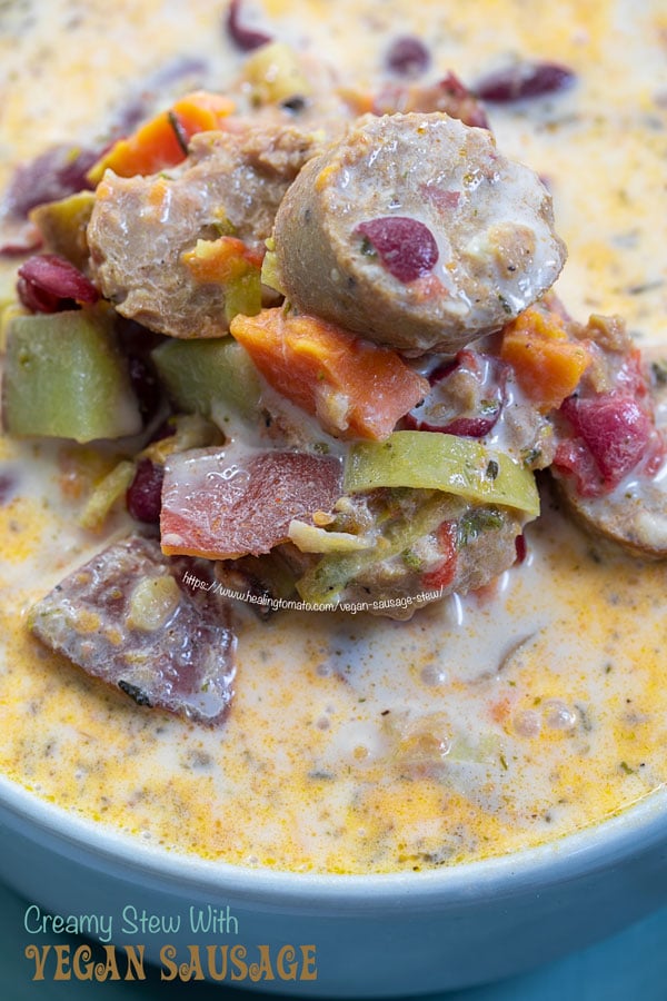 Closeup view of vegan sausage stew in a grey bowl