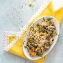 Top view of a risotto filled white oval plate over a yellow lace napkin