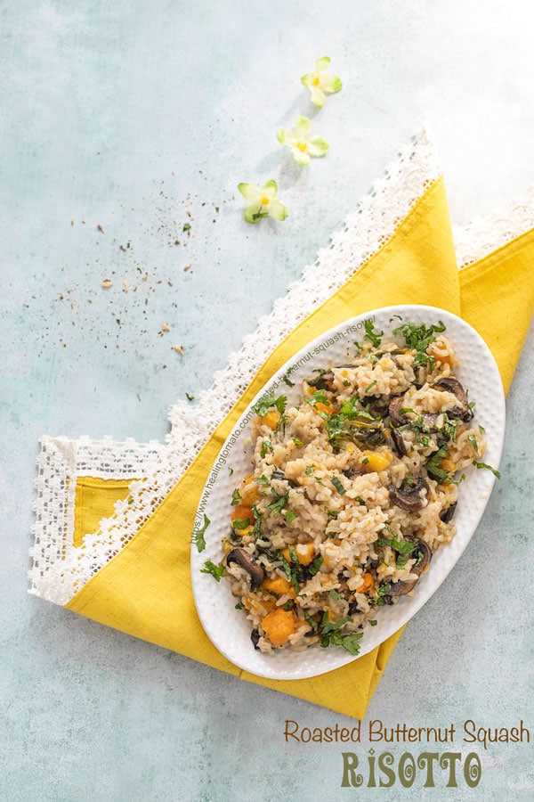 Top view of a risotto filled white oval plate over a yellow lace napkin