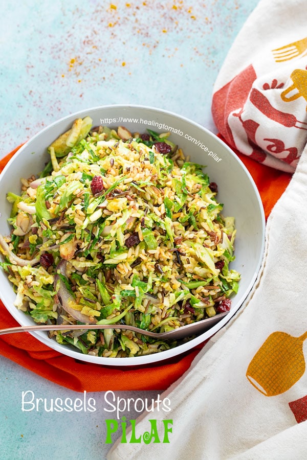 Top view of a grey bowl with Brussels sprouts pilaf over orange and white cloths