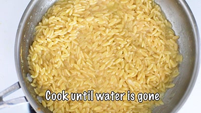 Water has gone from the pan and cooked orzo is visible