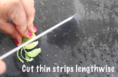 The author using a large kitchen knife to cut the sprout into thin strips