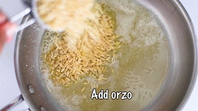 Uncooked orzo added to the pan