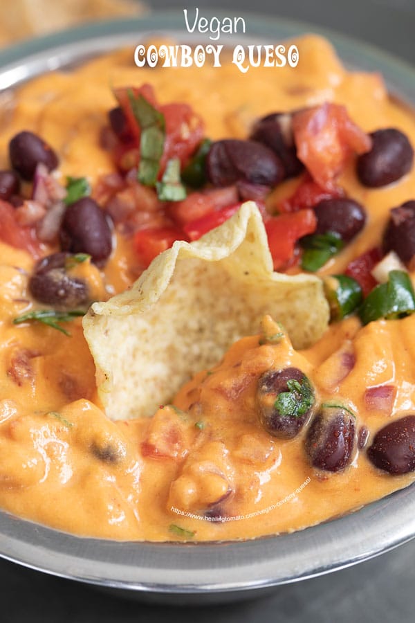 Closeup of the vegan cowboy queso with a tostitos scoop chip placed in the middle of the dip