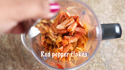 The author adding red pepper flakes to the blender