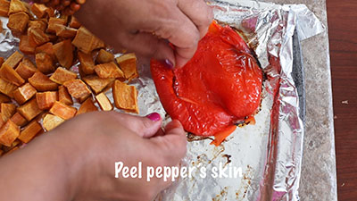 The author's hand peeling the red bell pepper