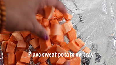 The author's hand showing sweet potatoes being placed on the baking tray