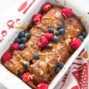 top and closeup view of vegan French toast bread pudding garnished with raspberries and blueberries with almond butter syrup lightly drizzled on top.