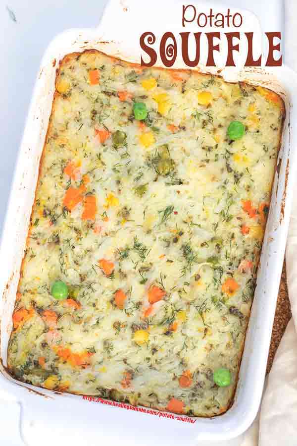 Closeup view of a white baking dish filled with mashed potato and vegetables souffle