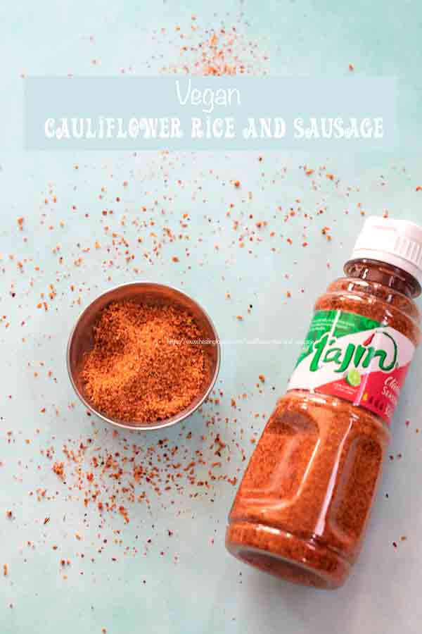 Top view of a small steel bowl filled with tajin spice. On the side a bottle of the tajin spice and some of the spice strewn around
