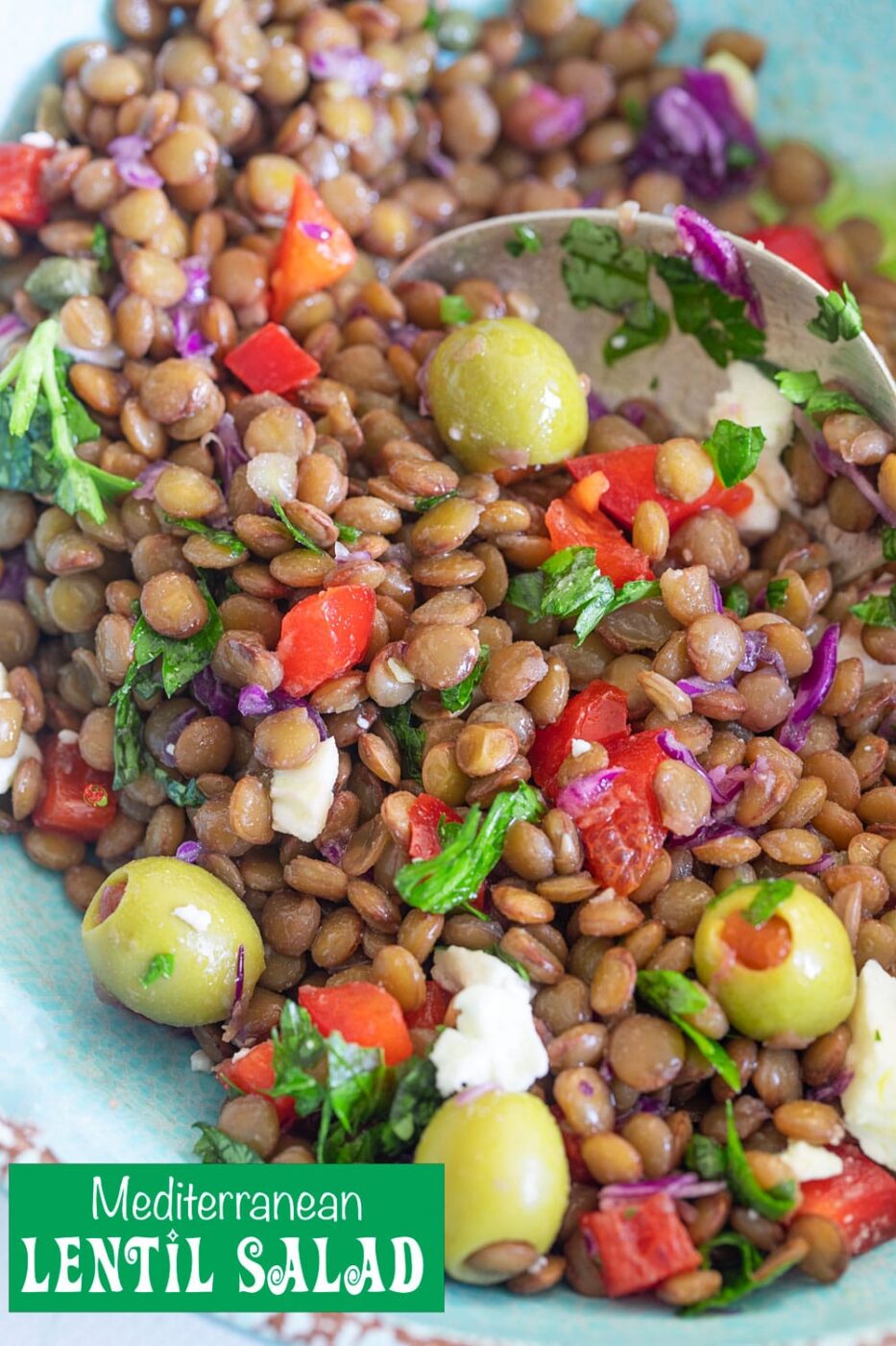 Closeup view of lentil salad in a light blue bowl with a spoon in it