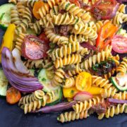 top view of fusilli pasta with grilled veggies on a black plate