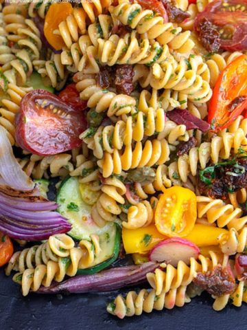 top view of fusilli pasta with grilled veggies on a black plate