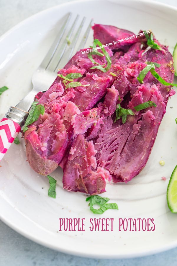 top view of a baked purple sweet potato on a white place with a spoon on the side and a fork on the left.