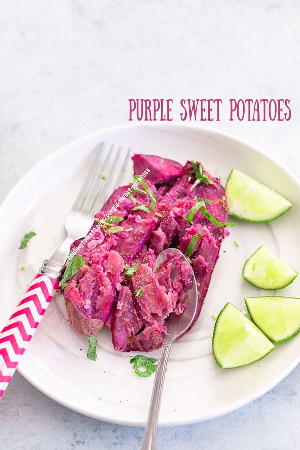 top view of a baked purple sweet potato on a white place with a spoon on the side and a fork on the left. Lemon pieces on the plate too.