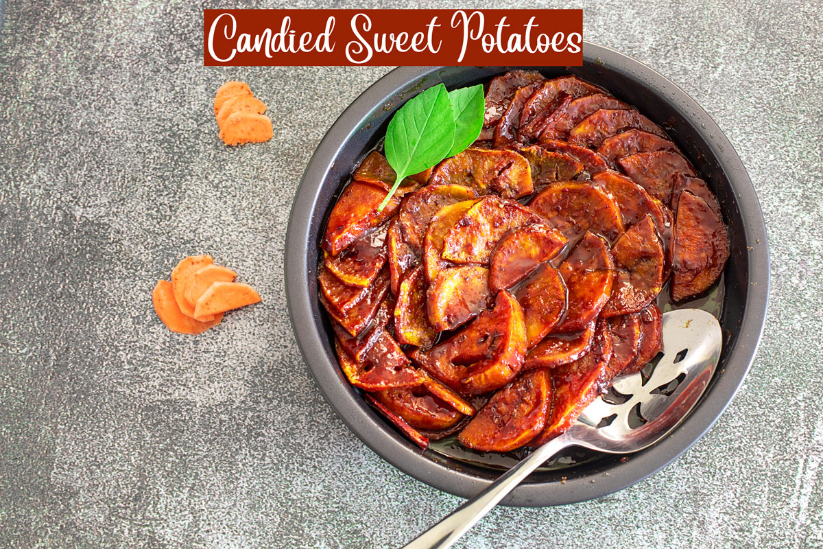 A top view of a pizza pan filled with the sweet potatoes, 2 basil leaves for garnish and a serving spoon on the side. Tiny crescent-shaped potatoes on the side of the pan for decorating.