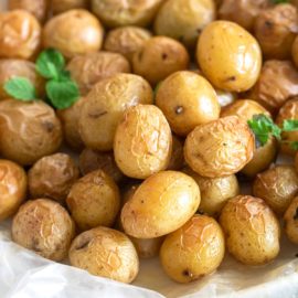 Front view of tiny potatoes in a garlic butter sauce put on a wax paper