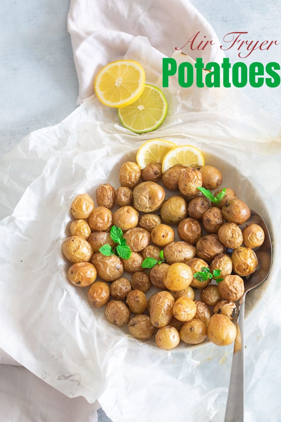 Overhead view of tasteful selection potato nibbles on white wax paper with a serving spoon on the side. Lemon rounds are also on the side.