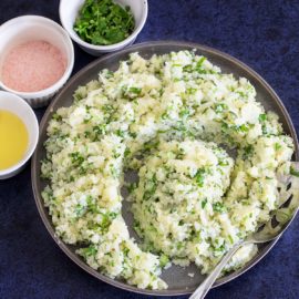 Top view of a grey plate filled with the cauliflower rice arranged in a somewhat spiral design