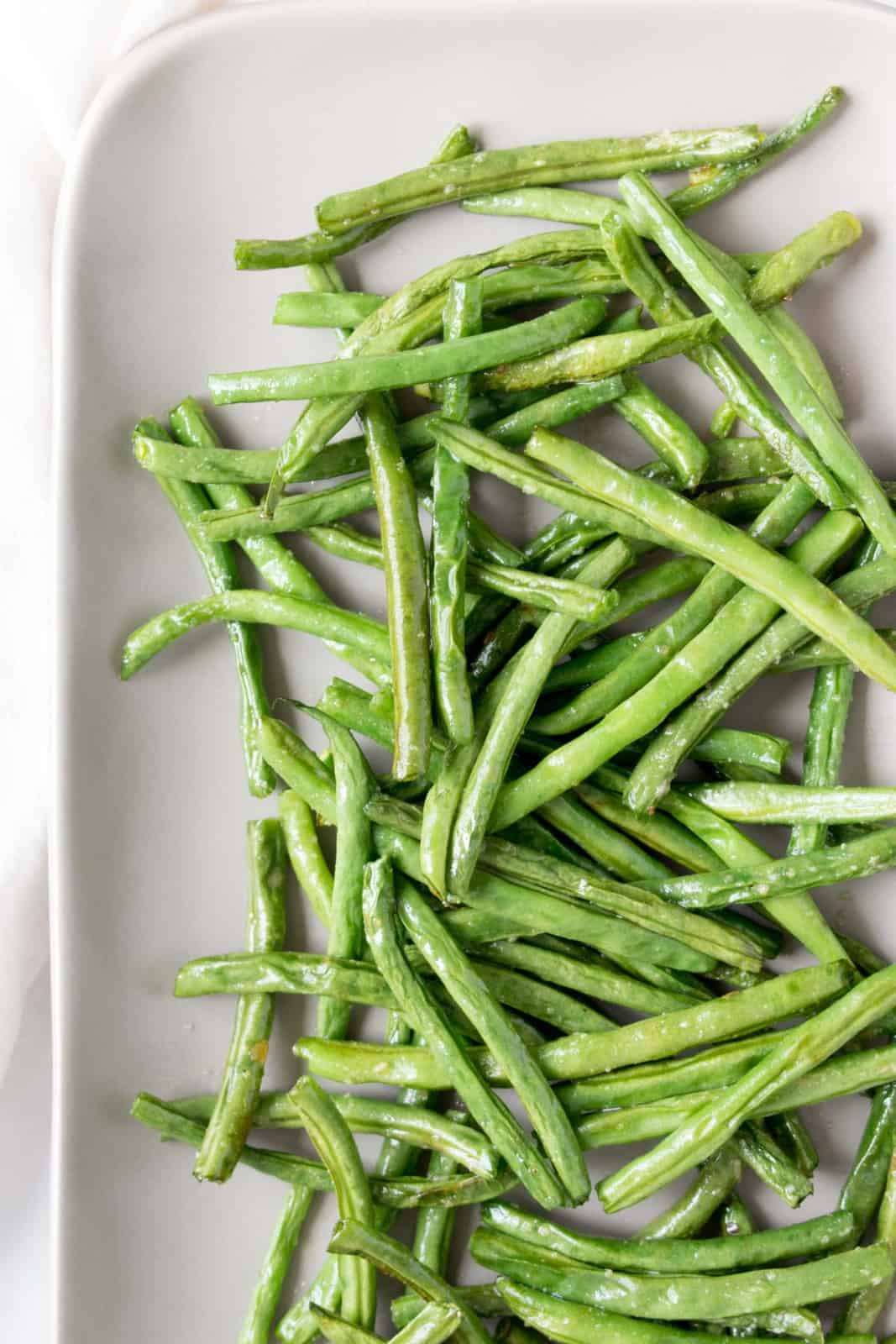 Top view of air fryer green beans on a white plate