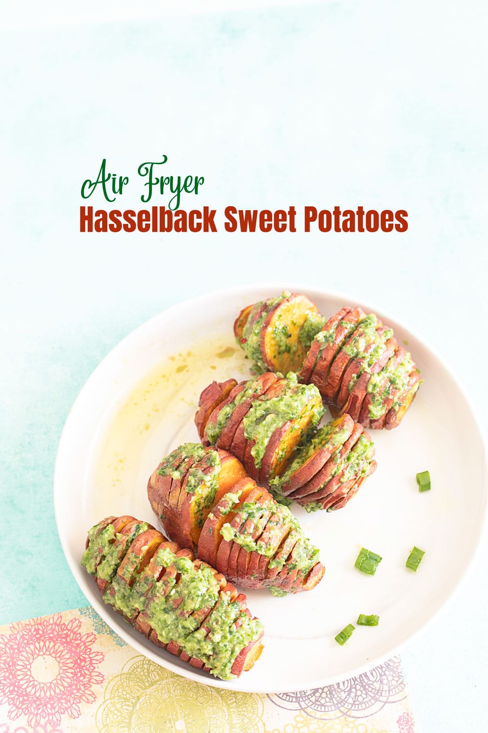 Top view of 4 baby hasselback sweet potatoes with a scallion pesto topping on a white plate